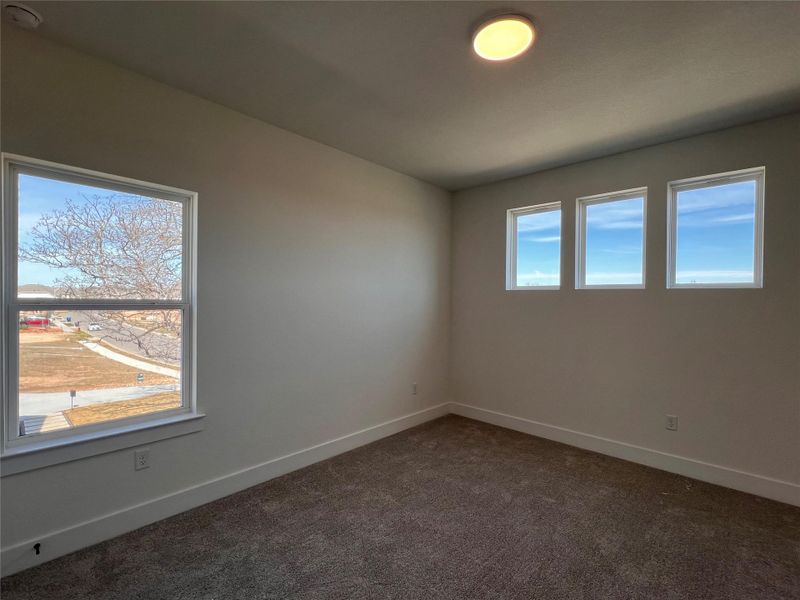 Empty room featuring dark colored carpet and baseboards