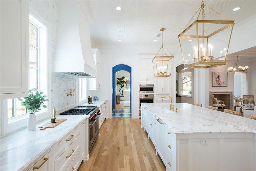 Kitchen featuring a center island with sink, premium range hood, appliances with stainless steel finishes, and a wealth of natural light