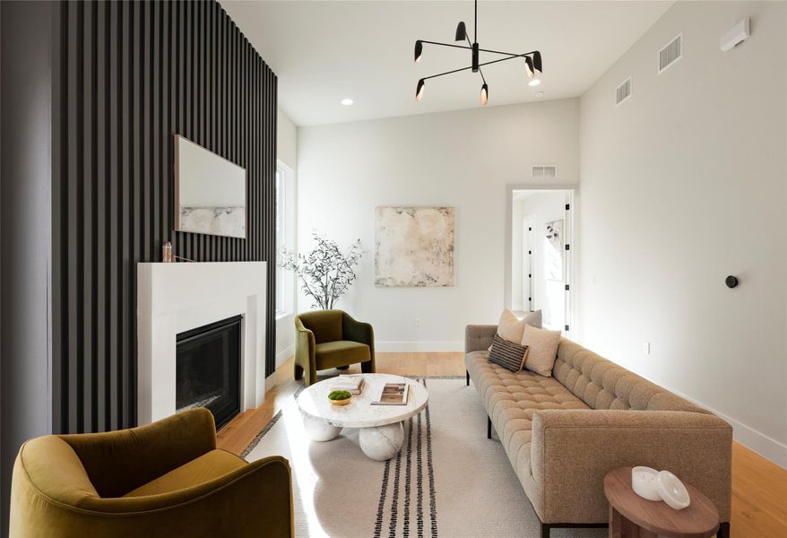 Living area featuring baseboards, visible vents, wood finished floors, and a glass covered fireplace