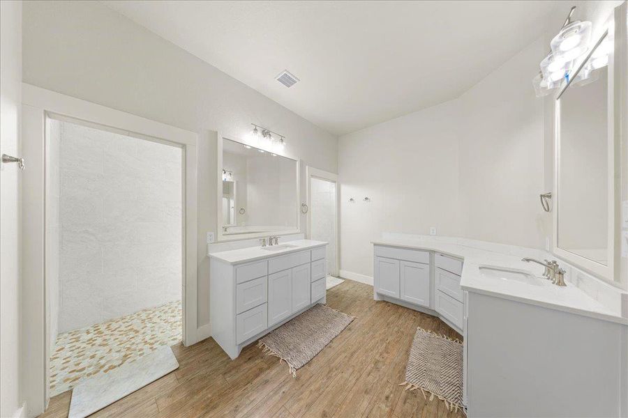 Bathroom with wood finished floors, two vanities, and a walk in shower Bathroom with wood finished floors, two vanities, and a walk in shower