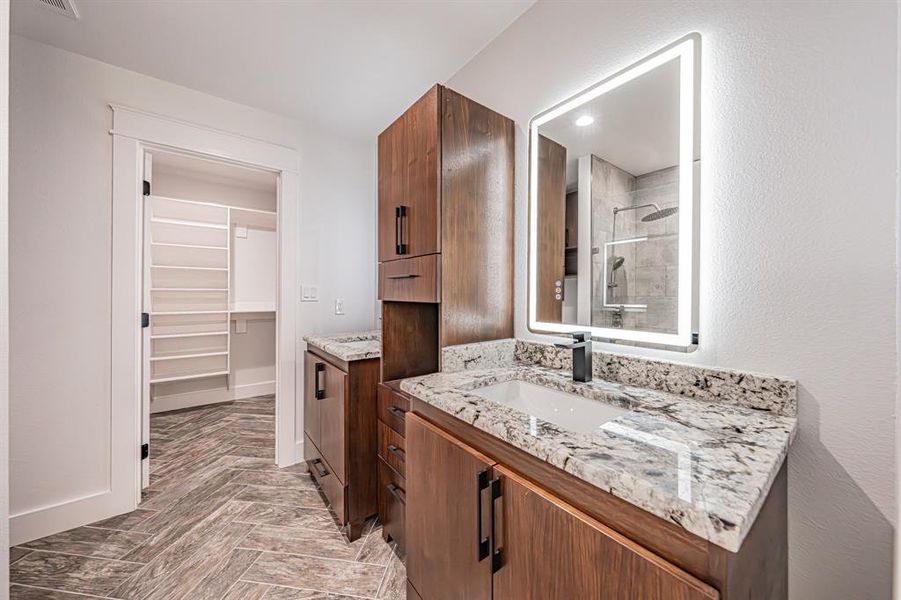 Bathroom featuring a shower stall, two vanities, and a spacious closet Bathroom featuring a shower stall, two vanities, and a spacious closet