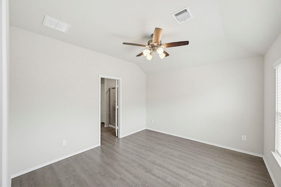 The Primary Bedroom located at the back of the home. Vaulted ceilings and a ceiling fan light fixture to keep your retreat cool and comfortable.