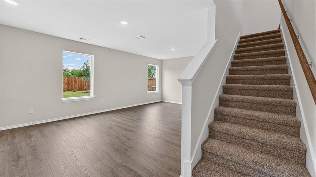 Open-concept living space featuring wood-finish flooring, recessed lighting, and bright windows Open-concept living space featuring wood-finish flooring, recessed lighting, and bright windows
