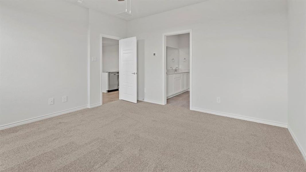 Unfurnished bedroom featuring light carpet, ensuite bath, and a ceiling fan