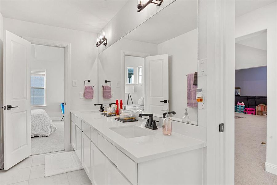 Ensuite bathroom featuring double vanity, tile patterned floors, a sink, and ensuite bath
