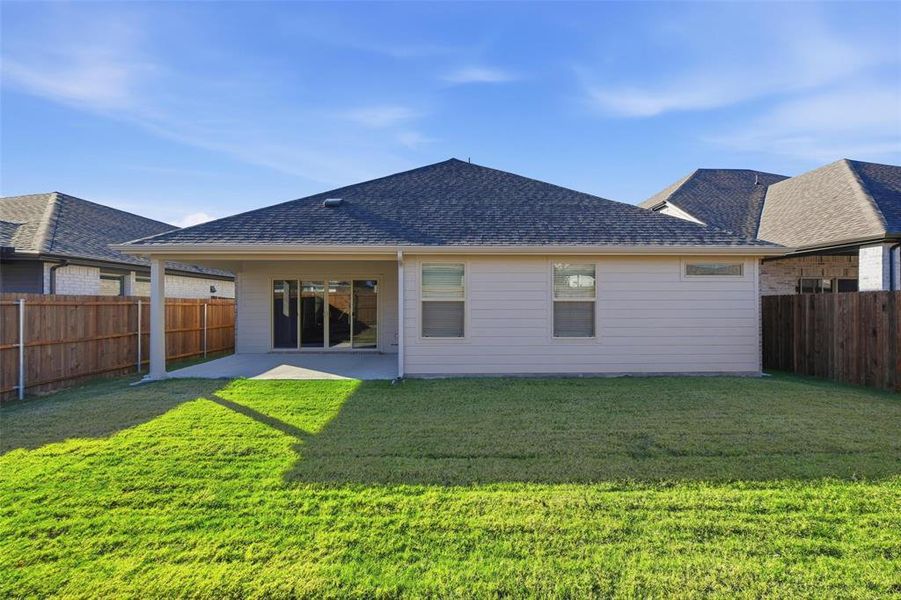 Back of property featuring a patio area, roof with shingles, and a fenced backyard