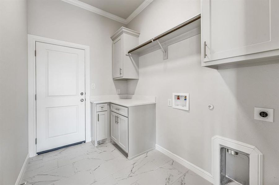 Laundry room featuring crown molding, gas dryer hookup, light marble finish floors, hookup for a washing machine, and cabinet space