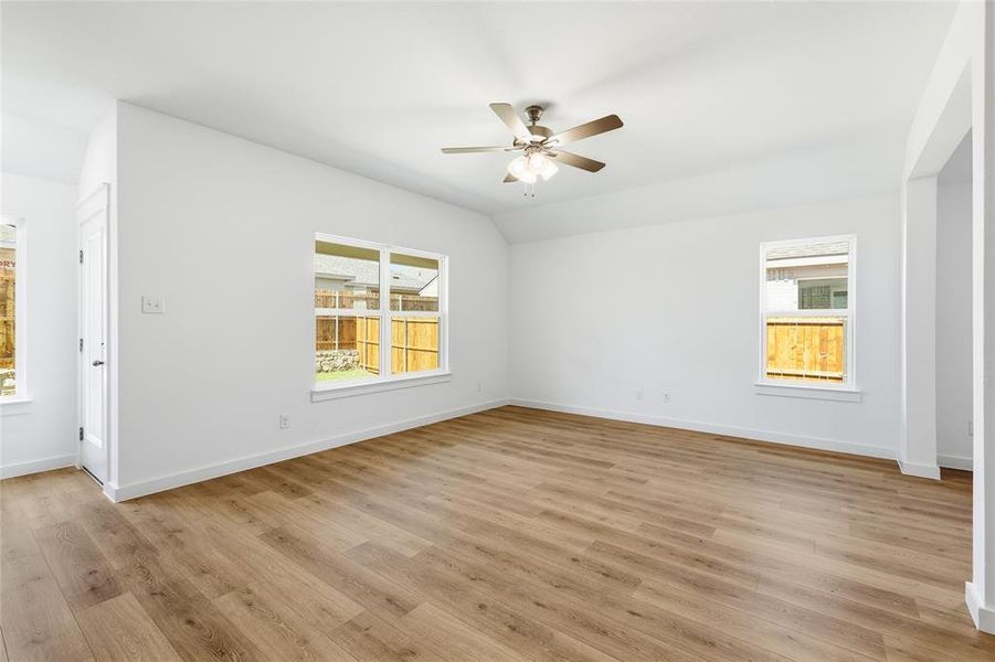 Empty room with light wood-style flooring, lofted ceiling, and ceiling fan