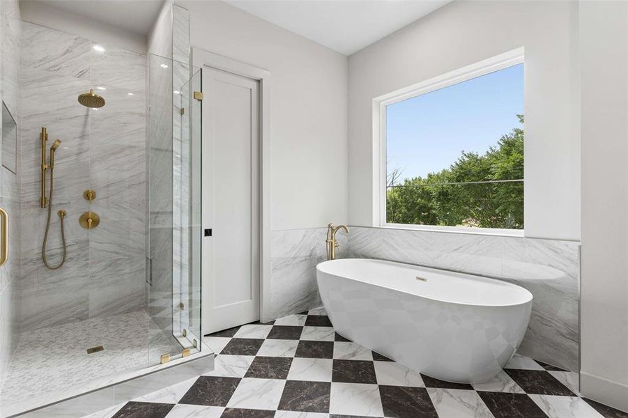 Contemporary bathroom featuring a freestanding soaking tub with gold-tone fixtures, a spacious walk-in shower with full-height tile surround and glass enclosure, and a large window. Contemporary bathroom featuring a freestanding soaking tub with gold-tone fixtures, a spacious walk-in shower with full-height tile surround and glass enclosure, and a large window.