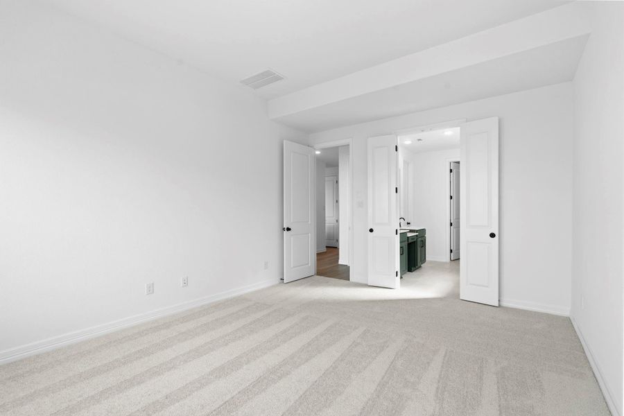 Serene primary suite with plush carpet and large windows—your perfect retreat to relax.