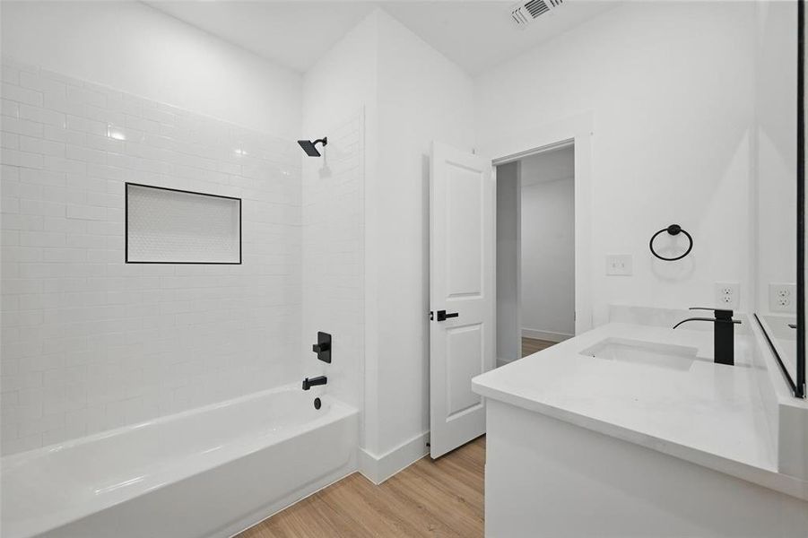 Bathroom with wood finished floors, double vanity, and  shower combination