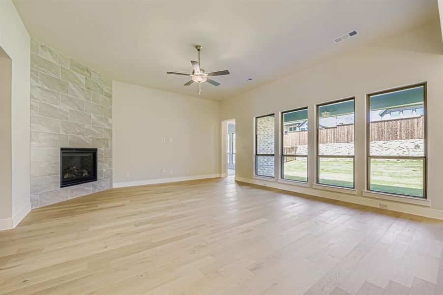 Unfurnished living room featuring a fireplace, light wood-style floors, and a ceiling fan