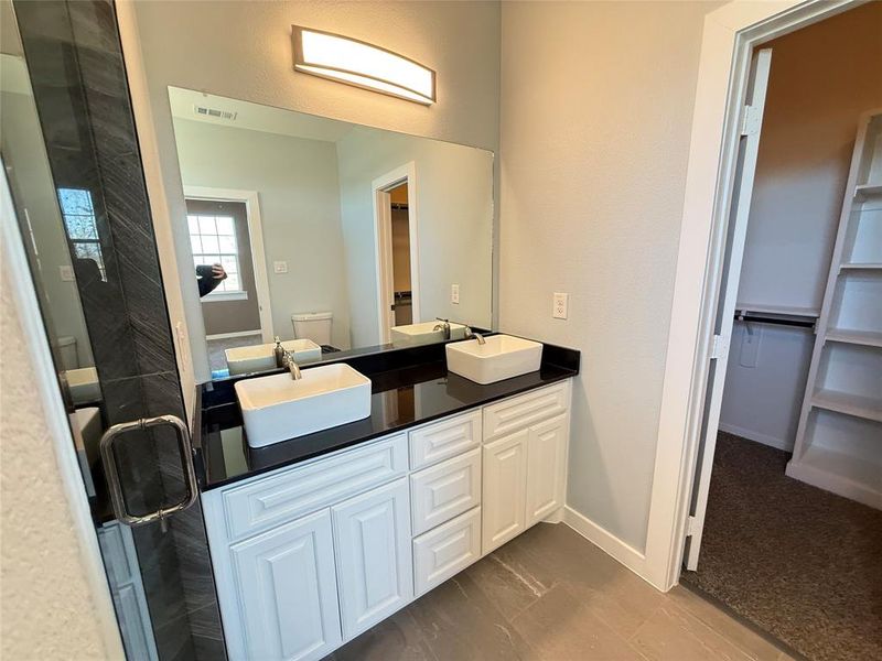 Bathroom featuring vanity, a shower with shower door, and toilet