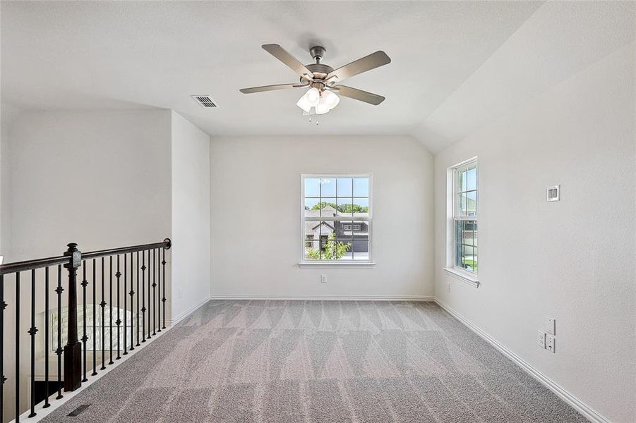 Carpeted spare room featuring ceiling fan and vaulted ceiling