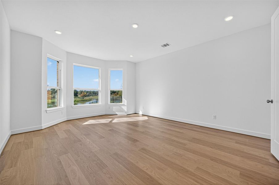 This view of the primary bedroom showcases its spacious layout and serene natural light. The large windows provide beautiful outdoor views, creating a calm and inviting atmosphere.