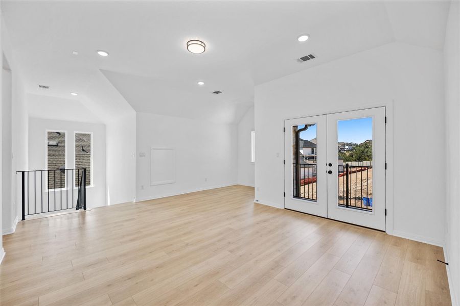 Unfurnished bonus/flex room with french doors, vaulted ceiling, light wood-style flooring, and recessed lighting