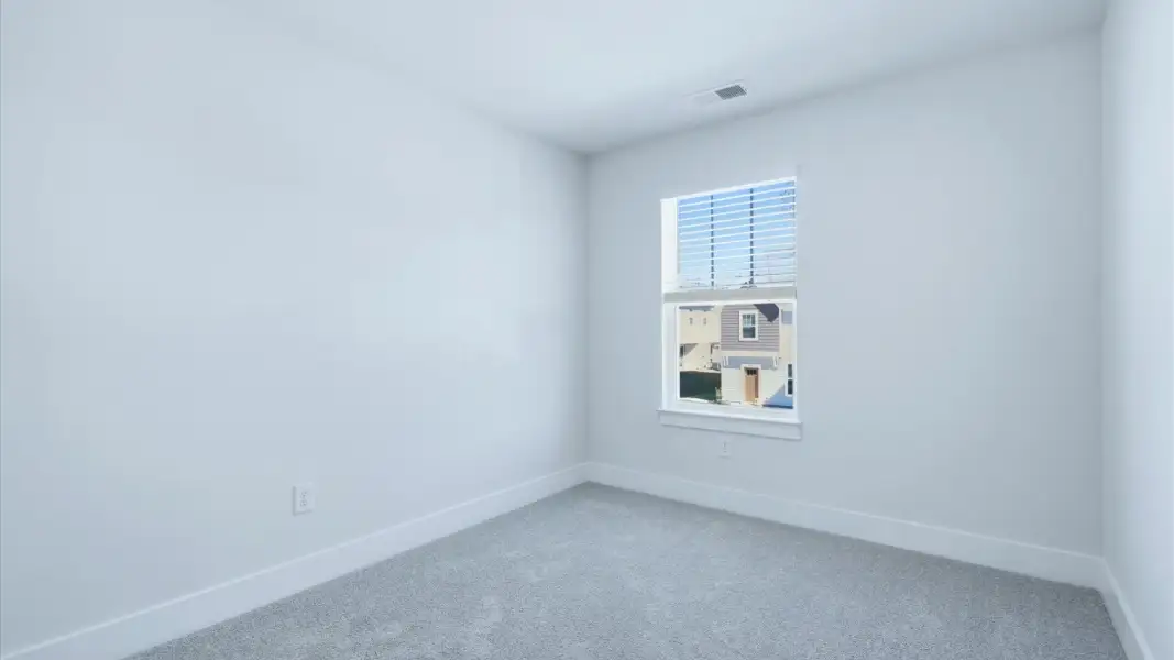 Superior comfort in this light-filled bedroom with plush carpeting and a thoughtfully placed large window at Clarke Townes