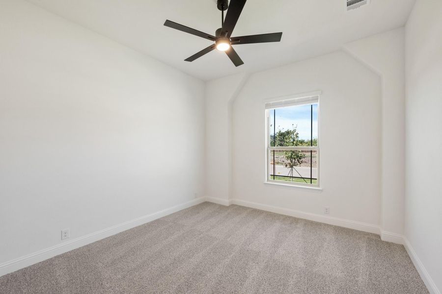 Empty bedroom with vaulted ceiling, black ceiling fan, carpet flooring, and single window Empty bedroom with vaulted ceiling, black ceiling fan, carpet flooring, and single window