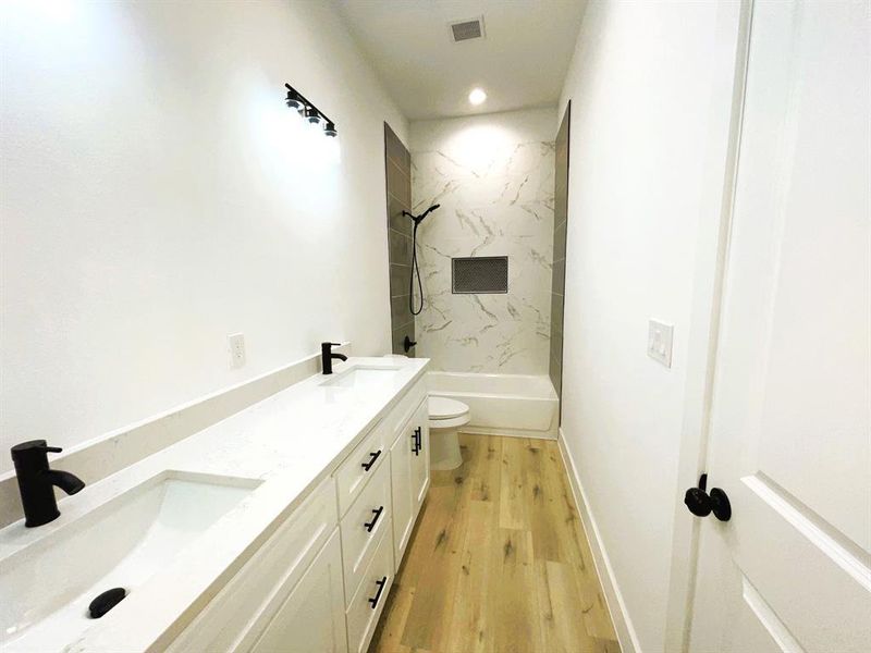 Full bathroom featuring toilet, tiled shower / bath, hardwood / wood-style flooring, and vanity