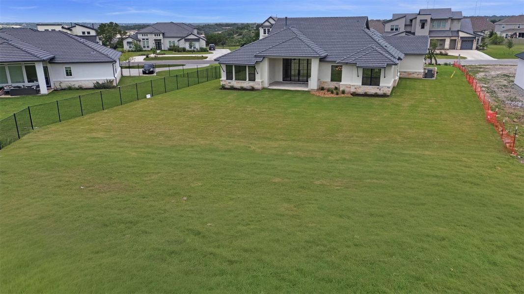 A manicured lawn surrounds this elegant, newly built home, offering a tranquil outdoor living space.