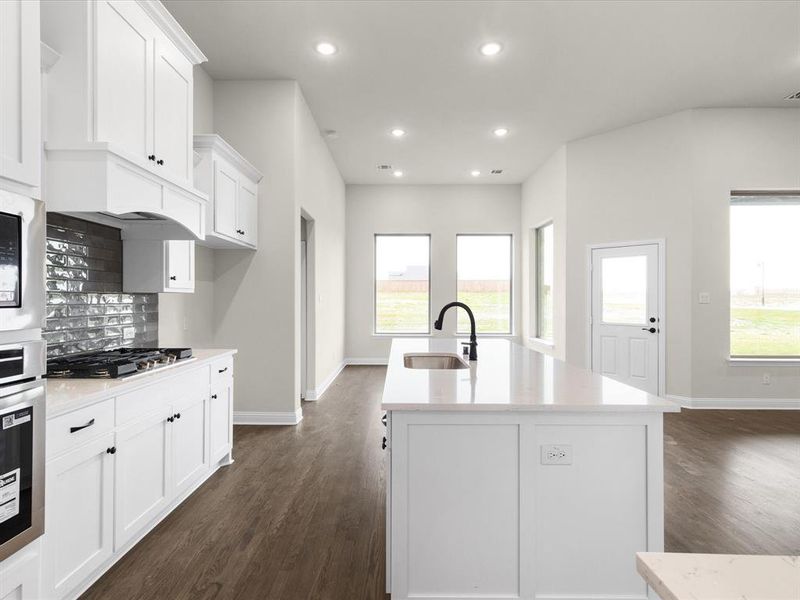 Kitchen featuring white cabinetry, recessed lighting, appliances with stainless steel finishes, light stone counters, and dark wood-type flooring