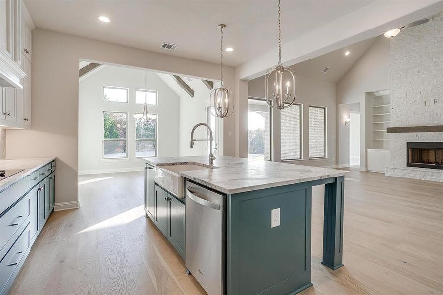 Kitchen with white cabinetry, a kitchen island with sink, a fireplace, and stainless steel dishwasher