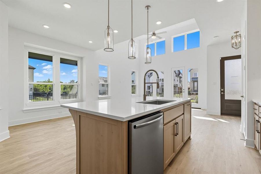 Kitchen featuring stainless steel dishwasher, a kitchen island with sink, hanging light fixtures, light wood finished floors, and recessed lighting Kitchen featuring stainless steel dishwasher, a kitchen island with sink, hanging light fixtures, light wood finished floors, and recessed lighting