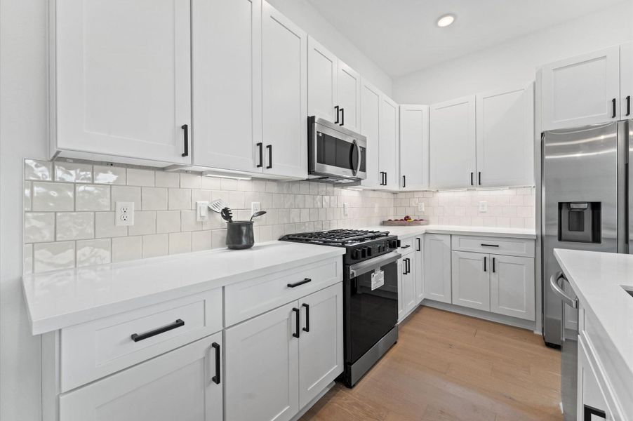 This stylish kitchen features sleek quartz countertops that offer both durability and elegance, paired with a spacious center island perfect for meal prep and casual dining. Surrounding the space is a generous array of cabinets, providing ample storage while maintaining a clean, streamlined look. The open layout and contemporary finishes create a welcoming atmosphere ideal for both everyday living and entertaining.