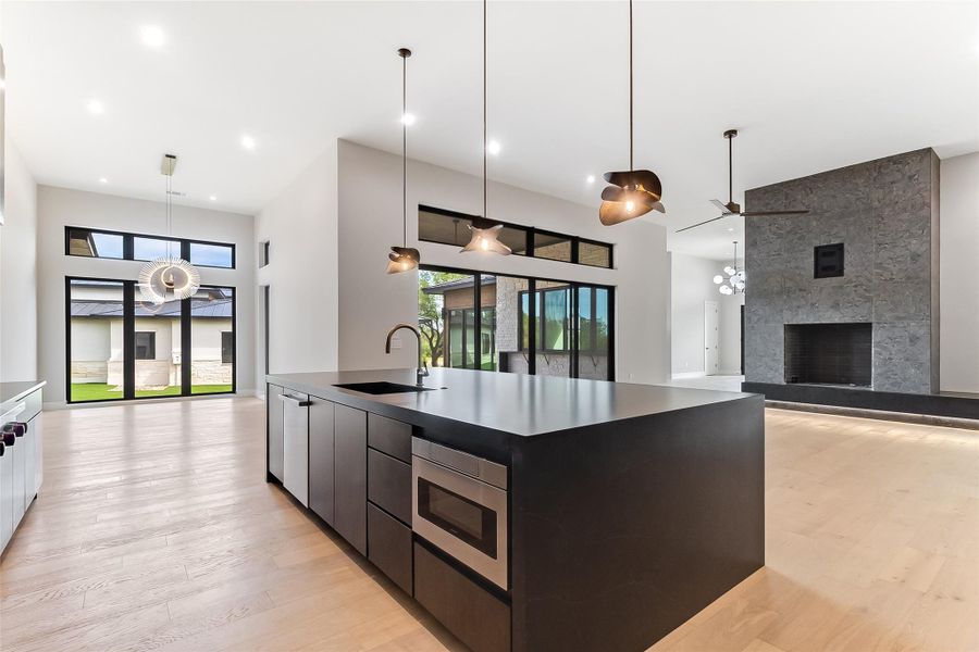 Kitchen with a sink, modern cabinets, healthy amount of natural light, stainless steel microwave, and a high ceiling Kitchen with a sink, modern cabinets, healthy amount of natural light, stainless steel microwave, and a high ceiling