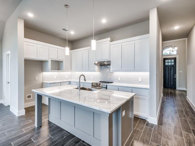 Kitchen with wood tiled floor, visible vents, under cabinet range hood, and a sink Kitchen with wood tiled floor, visible vents, under cabinet range hood, and a sink