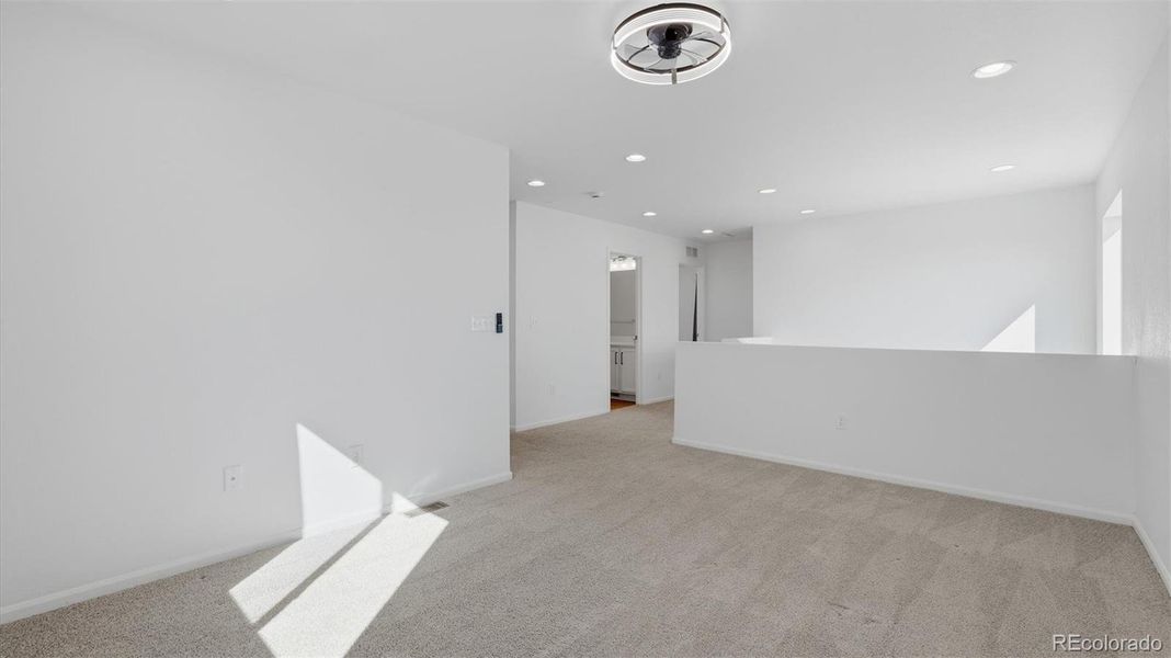 Spacious upper level Loft with ceiling fan and neutral carpet.