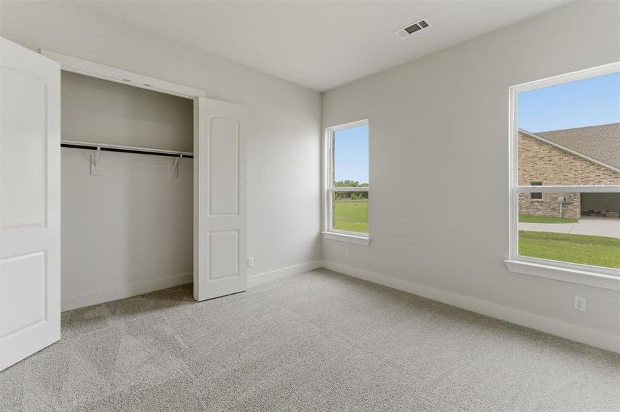Unfurnished bedroom featuring light carpet and a closet