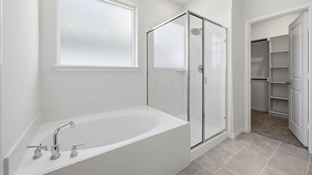 Bathroom featuring a soaking tub with chrome fixtures, a clear glass shower enclosure, a frosted privacy window, and tile flooring Bathroom featuring a soaking tub with chrome fixtures, a clear glass shower enclosure, a frosted privacy window, and tile flooring