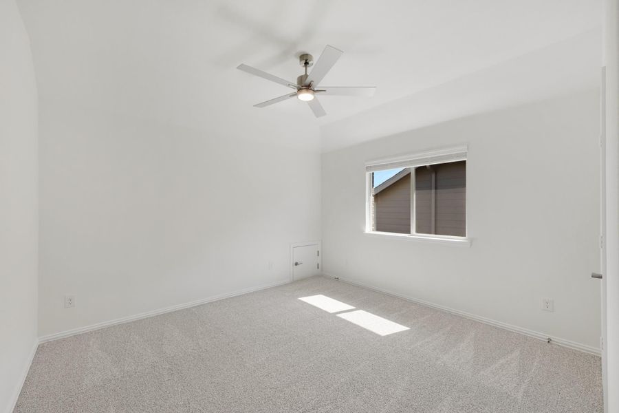 Empty bedroom with vaulted ceiling, ceiling fan, carpet flooring, and single window Empty bedroom with vaulted ceiling, ceiling fan, carpet flooring, and single window