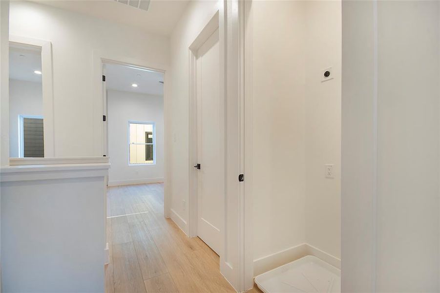 Corridor featuring light wood-type flooring and baseboards Corridor featuring light wood-type flooring and baseboards