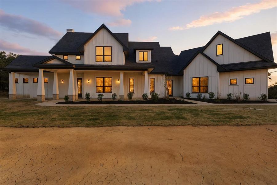 Modern farmhouse featuring board and batten siding, covered porch, roof with shingles, and a chimney Modern farmhouse featuring board and batten siding, covered porch, roof with shingles, and a chimney