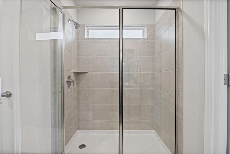 Tiled walk-in shower features glass sliding doors and a high transom window.
