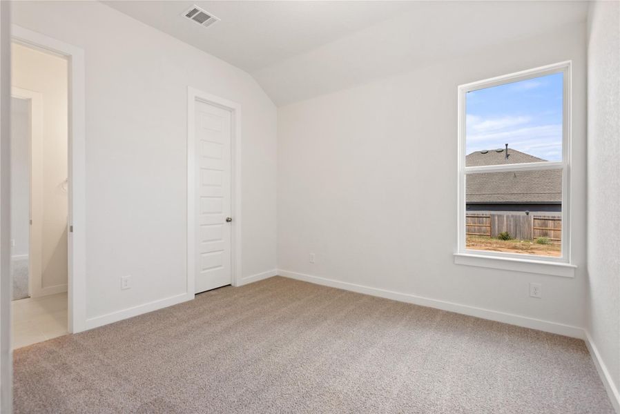 Unfurnished bedroom with multiple windows, light carpet, and lofted ceiling