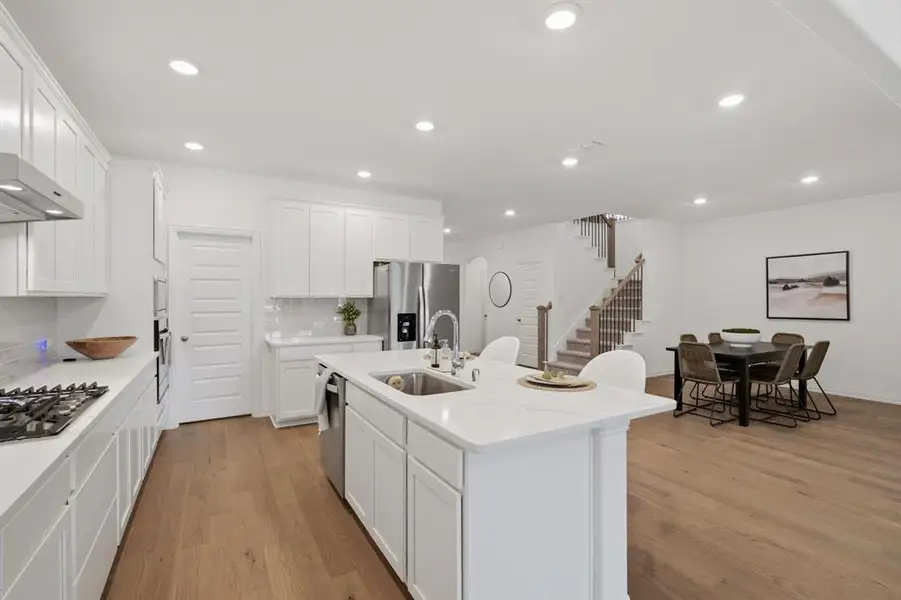 Bright white chef’s kitchen with quartz countertops, gas cooktop, stainless appliances, and a large island perfect for everyday living and entertaining.