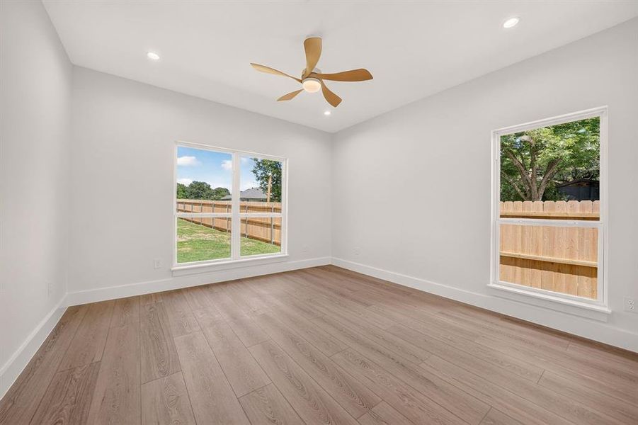 Spacious room featuring wood-finish flooring, white baseboards, and bright white walls