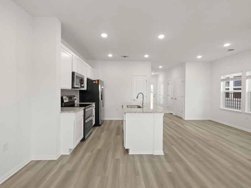 An open concept living area seamlessly connects to a modern kitchen featuring an island.