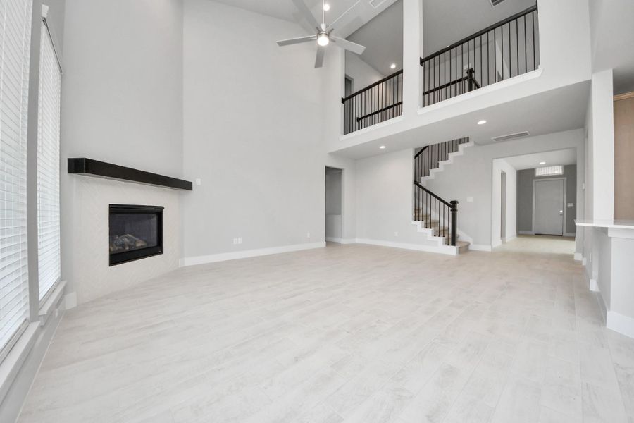 Welcome family and guests to your charming living room! With its high ceilings, recessed lighting, ceiling fan, custom paint, beautiful flooring, and large windows that let in abundant natural light, this room is perfect for gatherings.