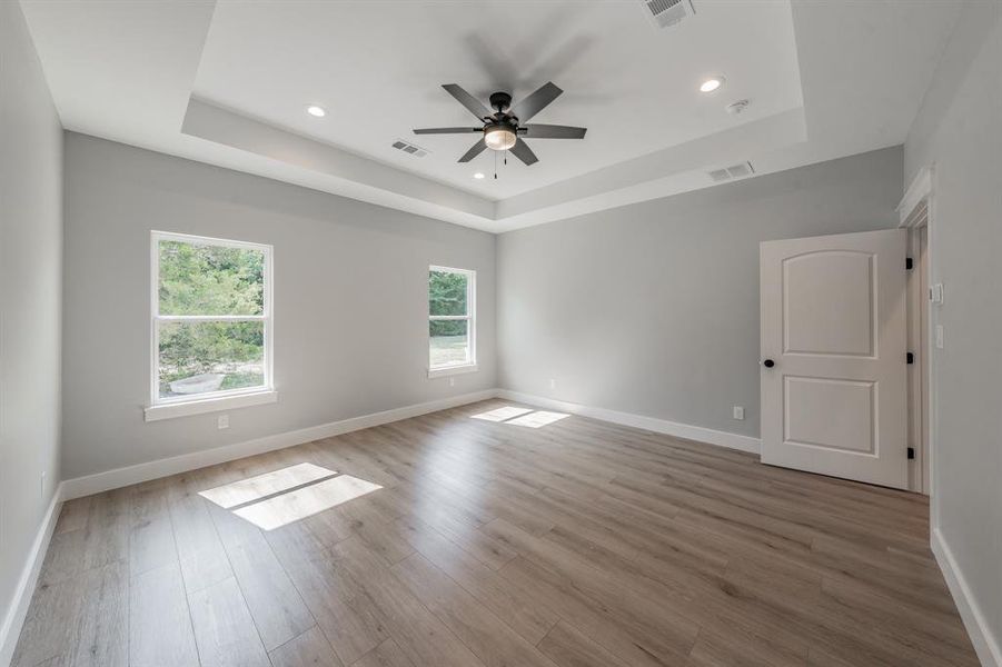 Spare room with ceiling fan, a raised ceiling, and hardwood / wood-style floors