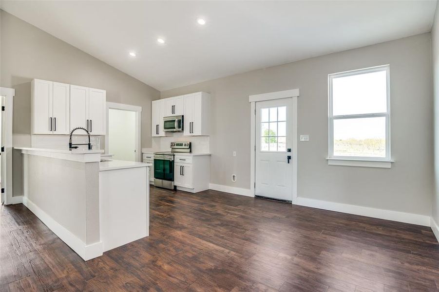 Kitchen featuring sink, dark hardwood / wood-style floors, kitchen peninsula, white cabinets, and appliances with stainless steel finishes