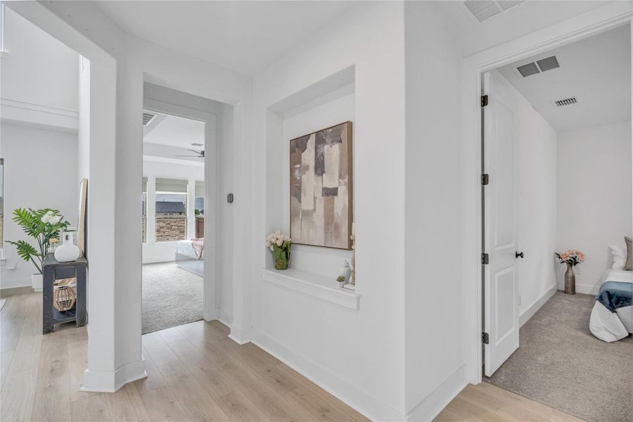 Luminous hallway connects vibrant living spaces with hardwood and soft carpeted flooring.