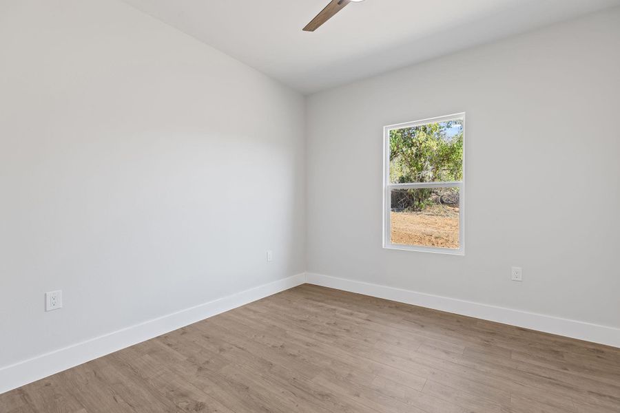 Empty room featuring wood finished floors and a ceiling fan