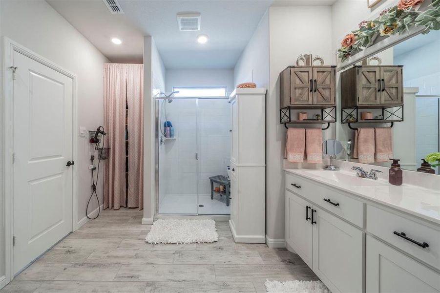 Bathroom featuring hardwood / wood-style floors, vanity, and an enclosed shower