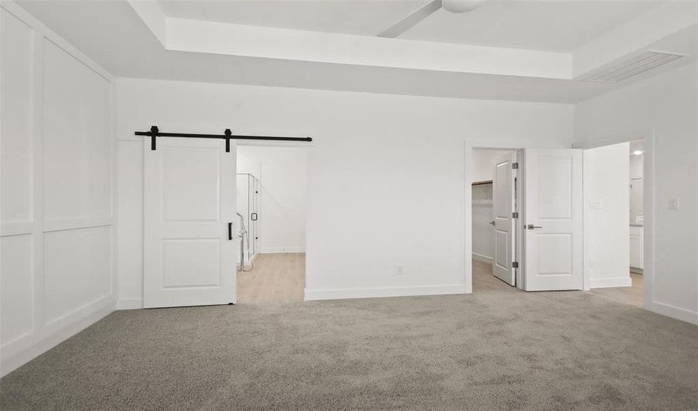 Relaxing primary suite with barn door to primary bath