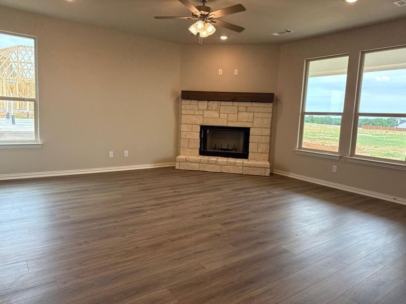 Corner fireplace featuring stone surround and a wood mantel
