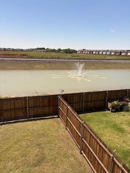Private backyard space featuring a wood fence, green lawn, and water feature with a fountain